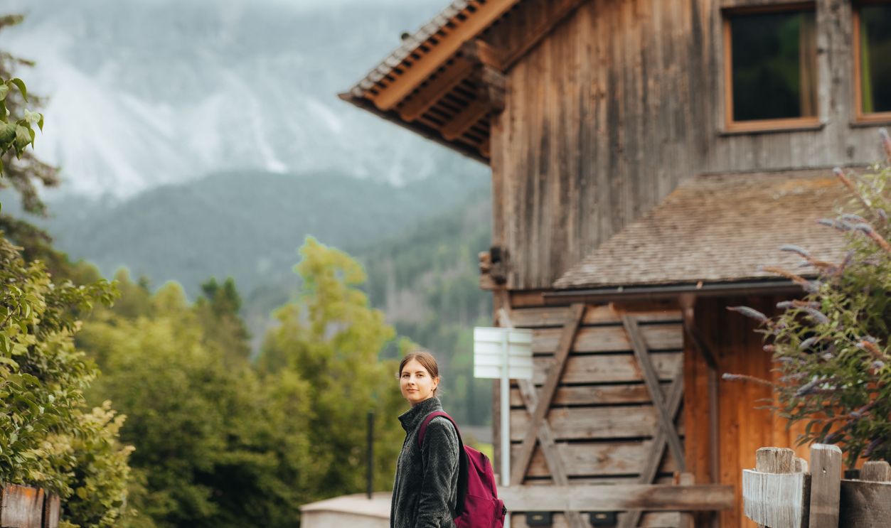 Woman enjoys a serene hike near a charming wooden cabin in the mountains