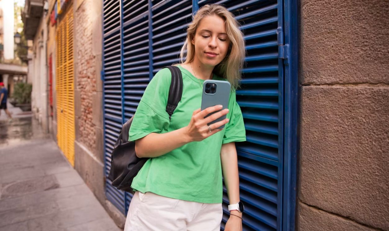 a woman in a green shirt is looking at her cell phone