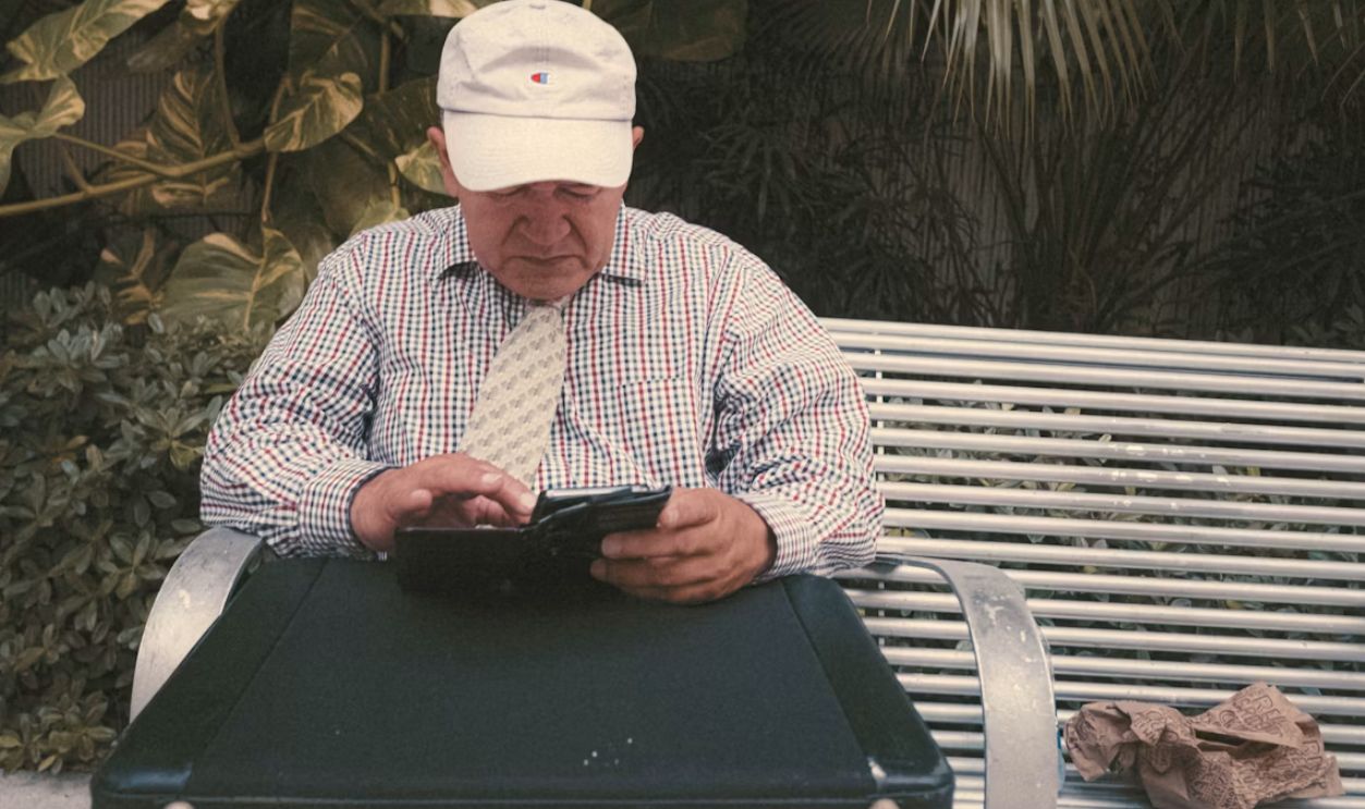 a man sitting on a bench looking at his cell phone