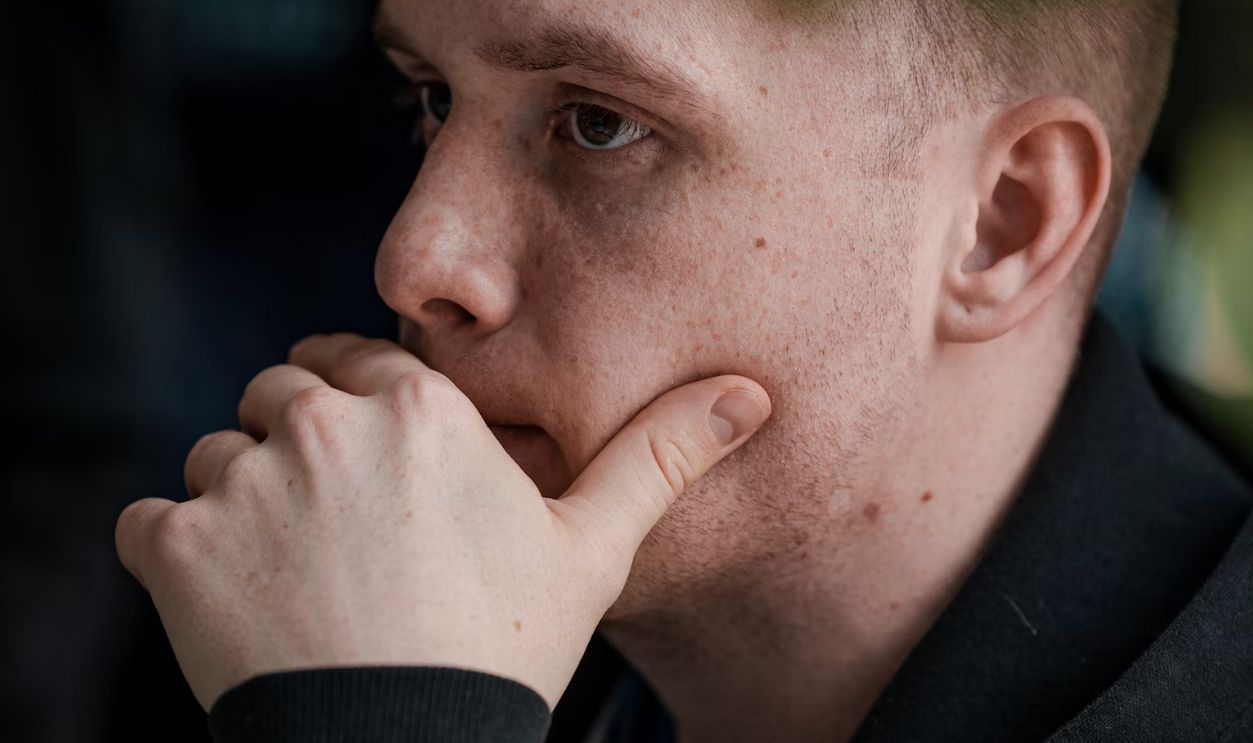 man in black jacket covering his mouth