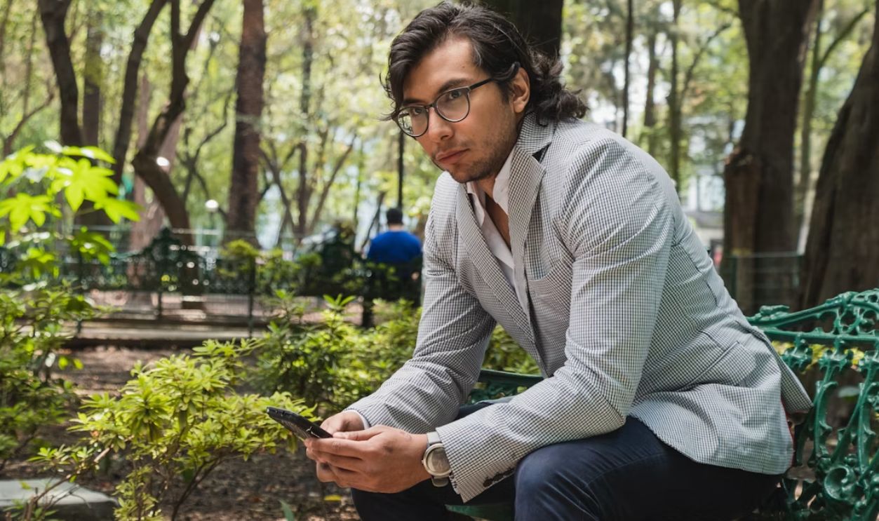 Man sitting on a park bench with phone.