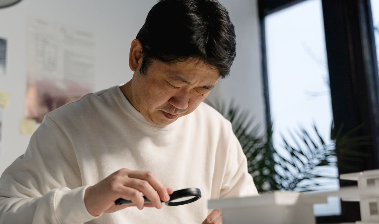 Focused architect examines detailed blueprints using a magnifying glass