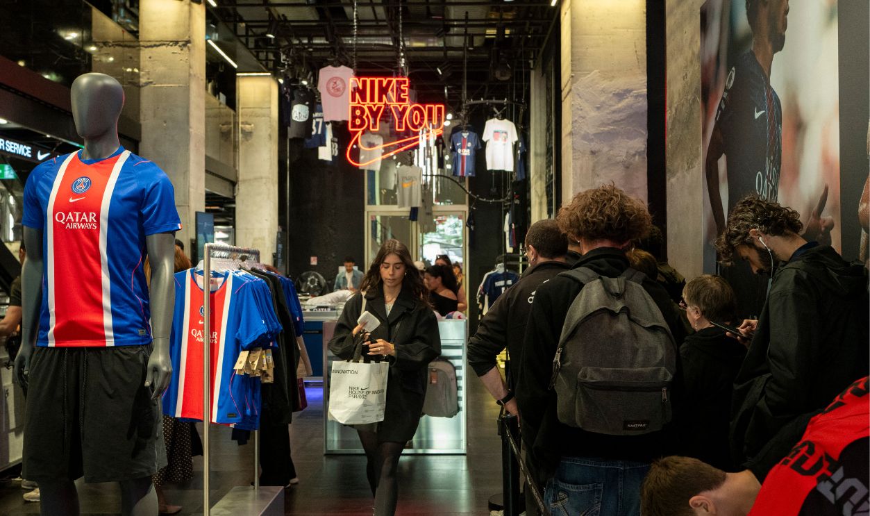 Interior view of the Paris Saint Germain NIKE official store on the Champs Elysees with customers browsing football jerseys and merchandise displayed beside a UEFA Champions League themed promotional wall in Paris in Ile de France in France on June 5, 2026. The scene shows entry of the store with PSG jerseys.