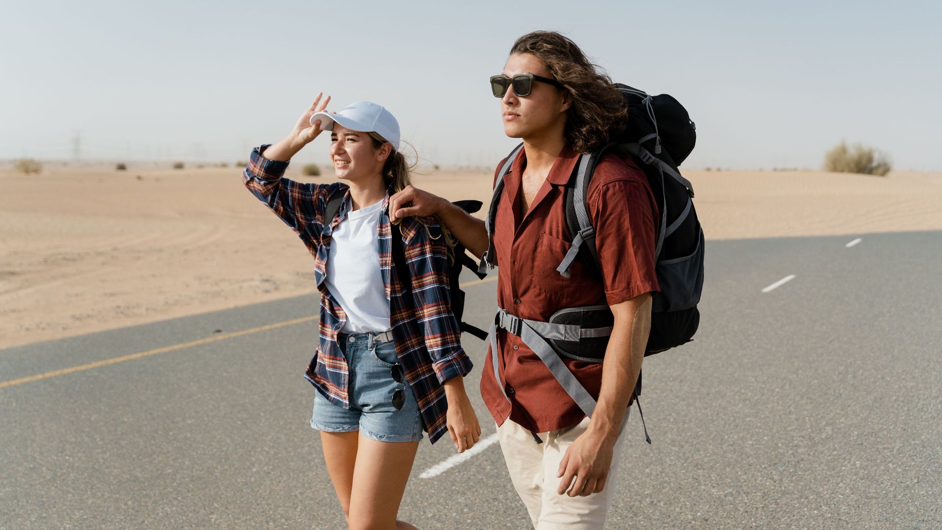 Young couple backpacking through a desert road, capturing wanderlust and exploration.