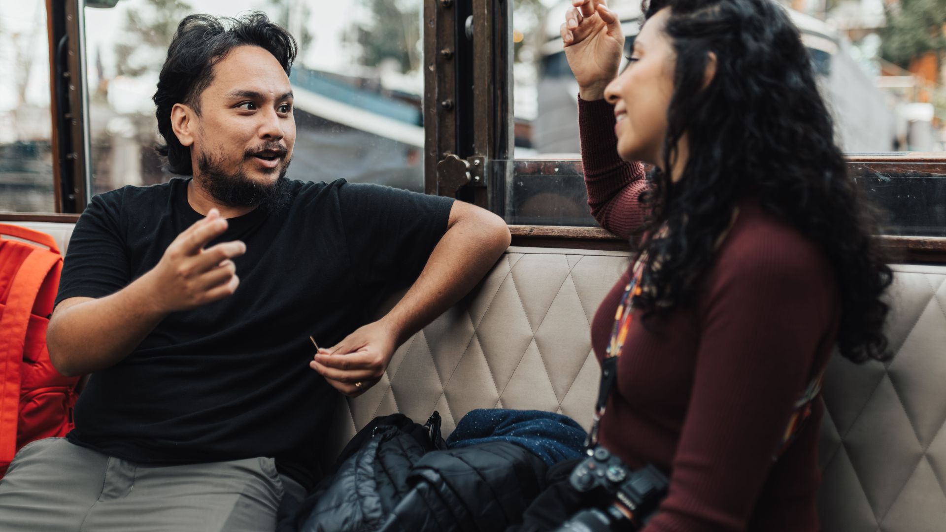 A couple enjoys a lively conversation while traveling on a tram, capturing the essence of public transportation.
