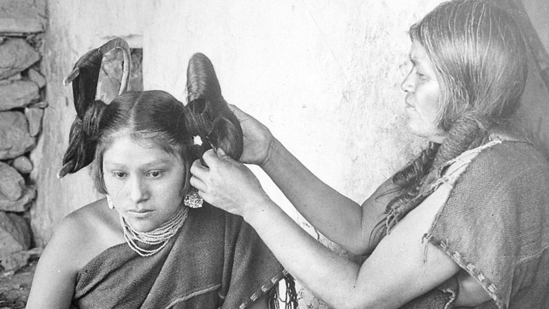 Hopi woman dressing hair of unmarried girl, 1900.