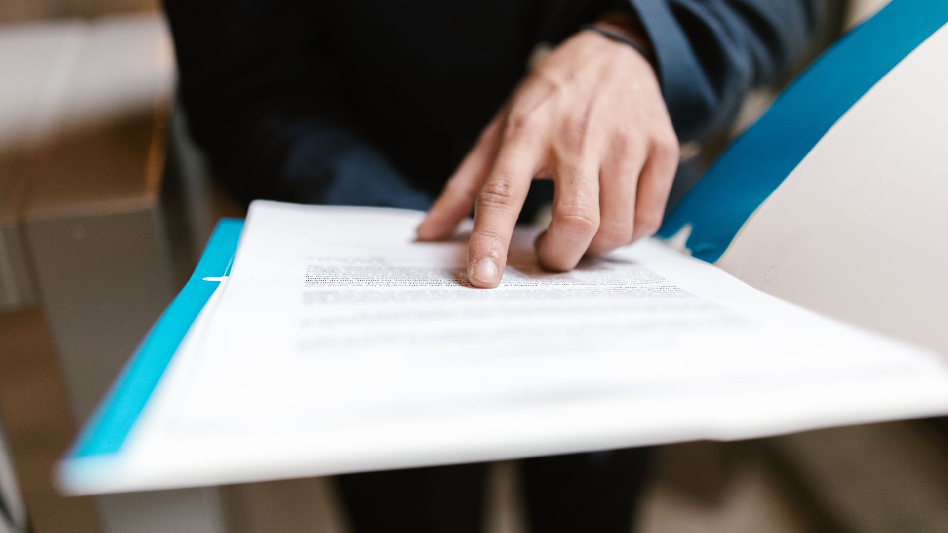 Close-up of a hand pointing at text on a business document in an office environment.