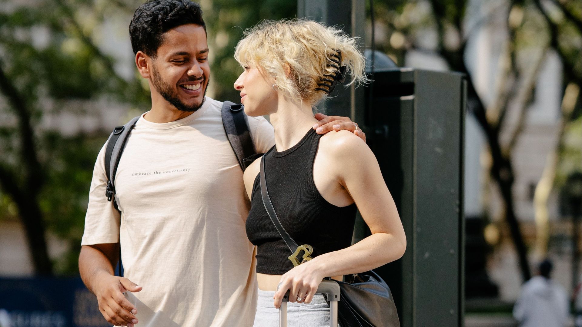 Smiling couple with suitcase standing together on a city street