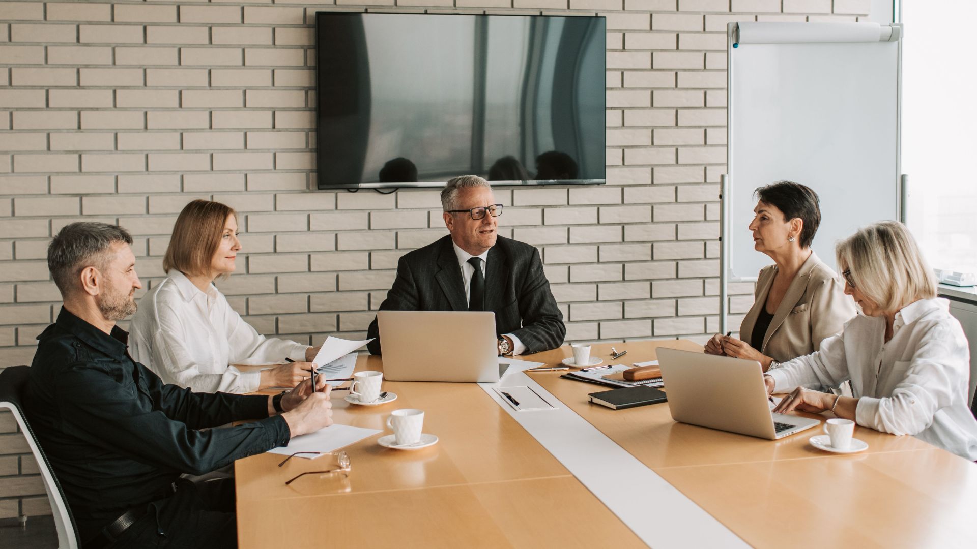 A professional team meeting with laptops and documents in a modern office.