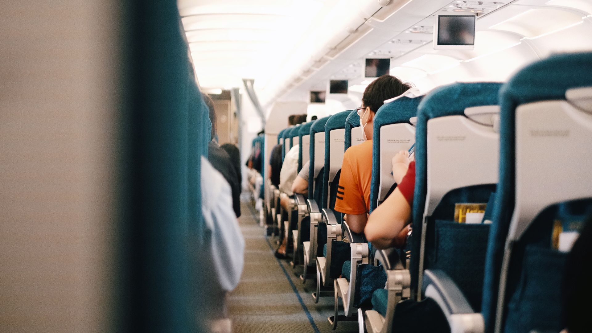 Interior view of airplane cabin showing passengers seated during a flight.