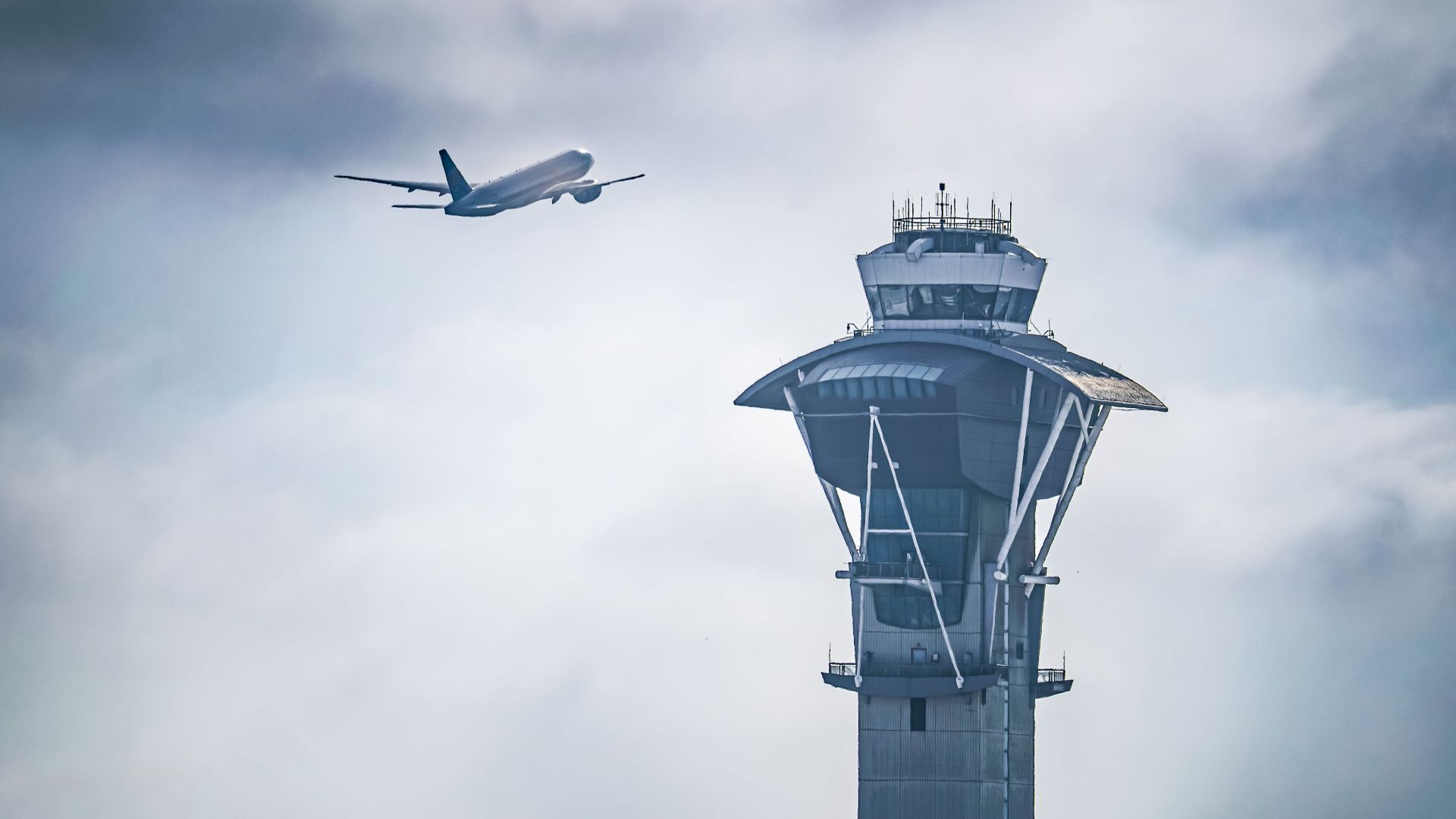 Dramatic shot of an airplane taking off near the iconic LAX control tower in Los Angeles, California.