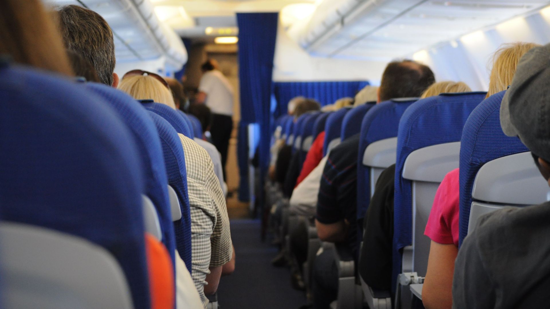 Interior view of an airplane cabin with passengers seated, showcasing air travel experience.