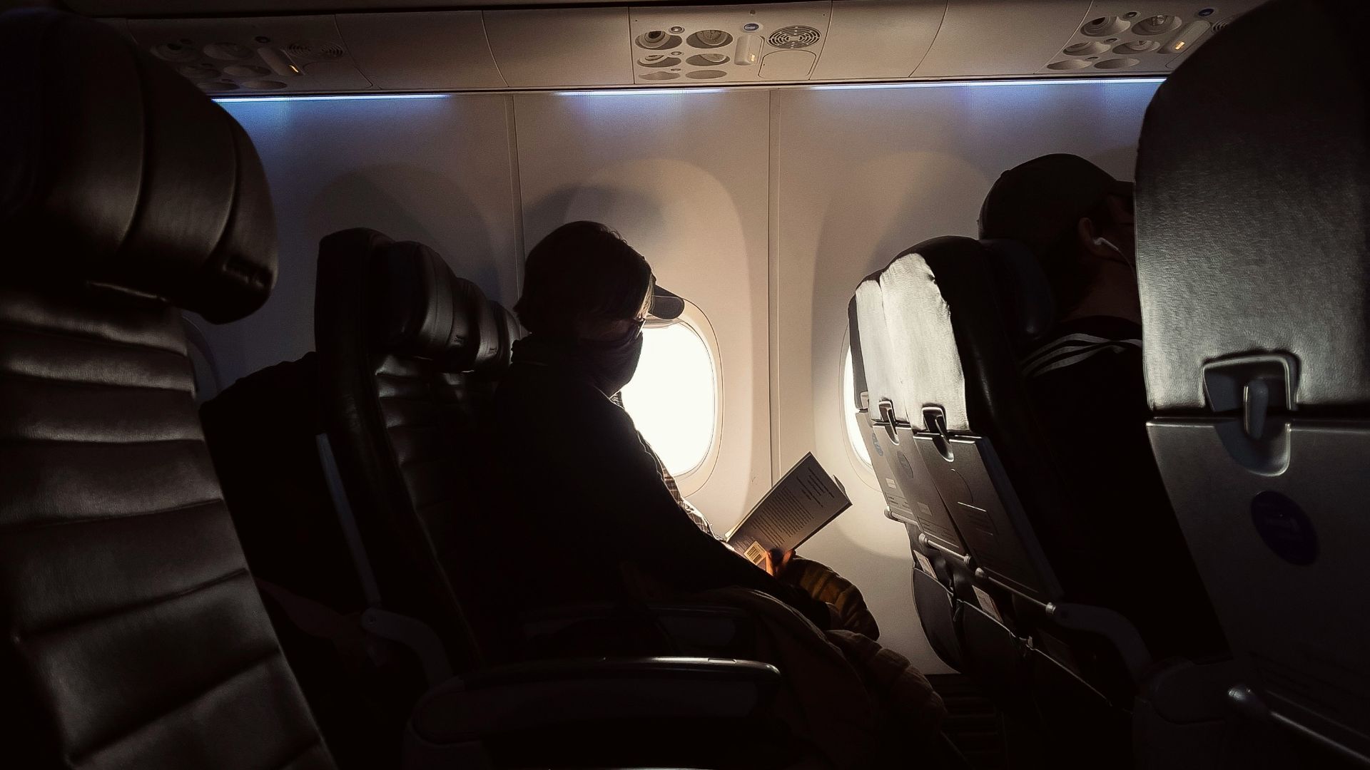 man in black jacket sitting on airplane seat