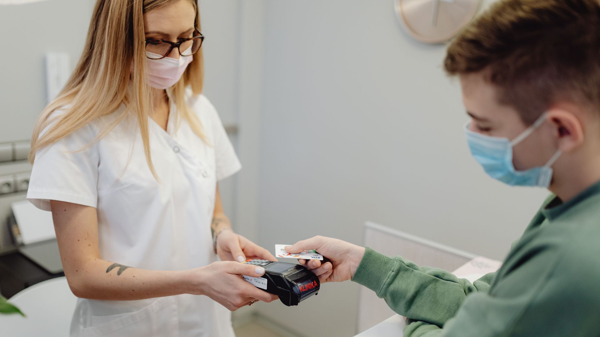 A healthcare professional processes a patient's card payment at the clinic reception.