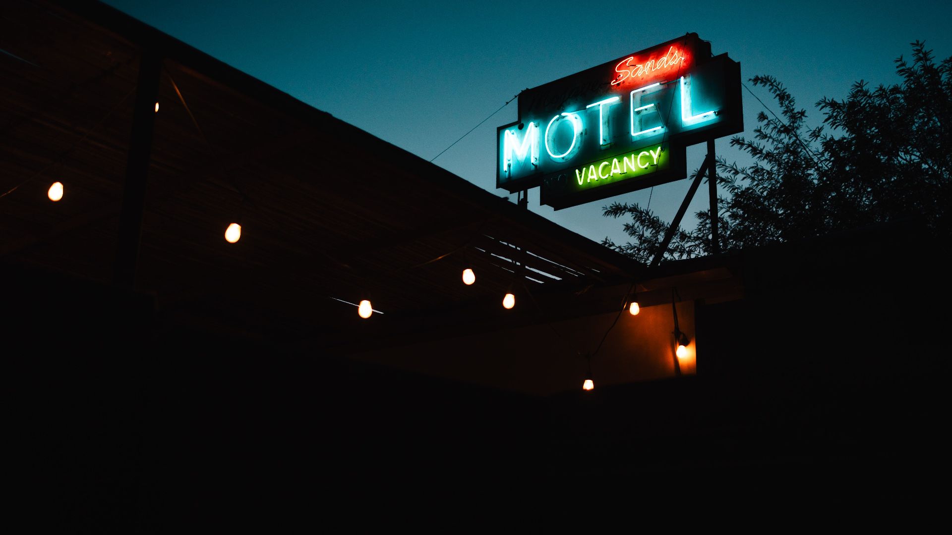 Atmospheric shot of a classic neon motel sign glowing in the evening light, indicating vacancy.