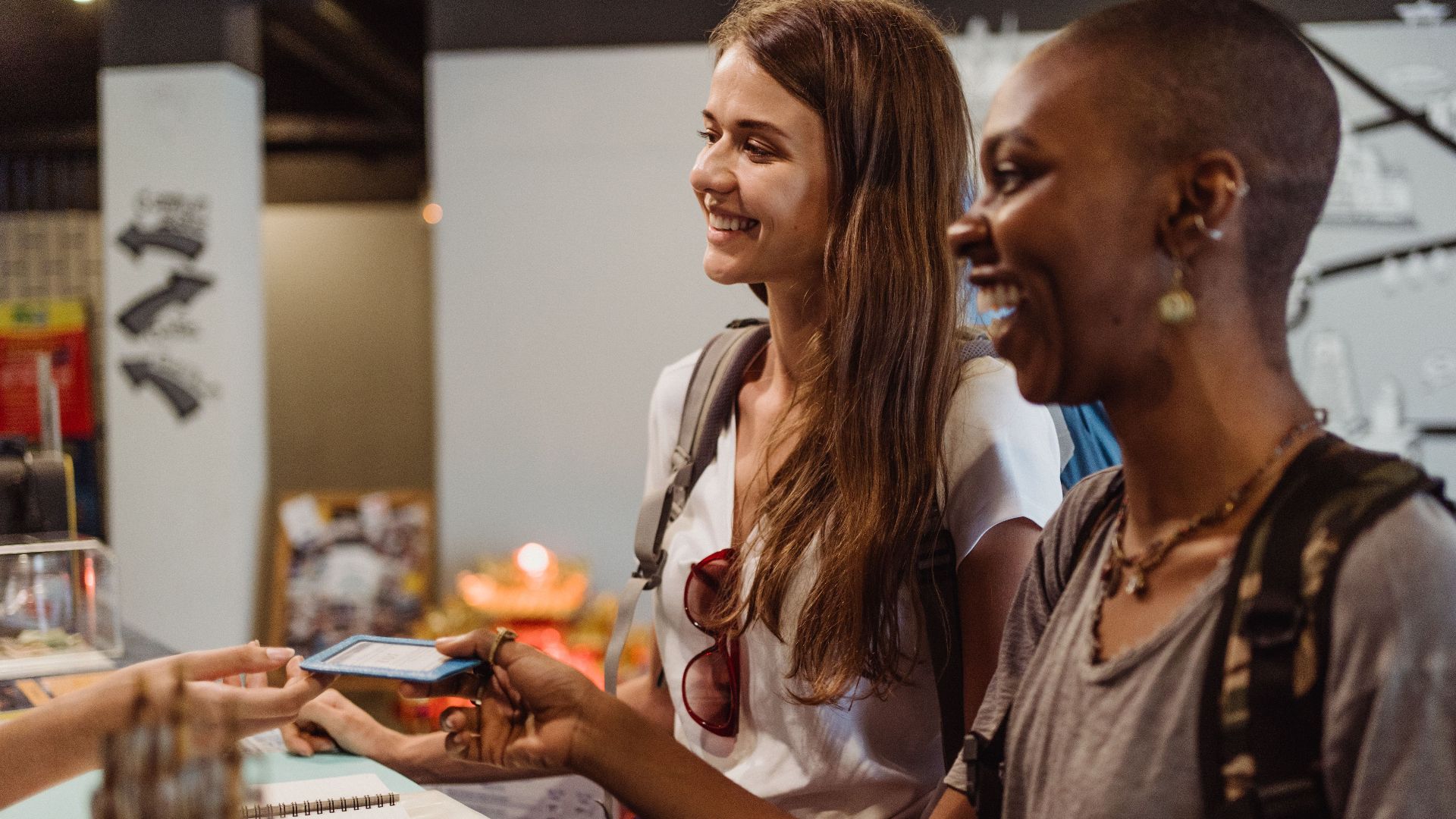 Two women enjoying a cheerful check-in at a hostel reception desk.