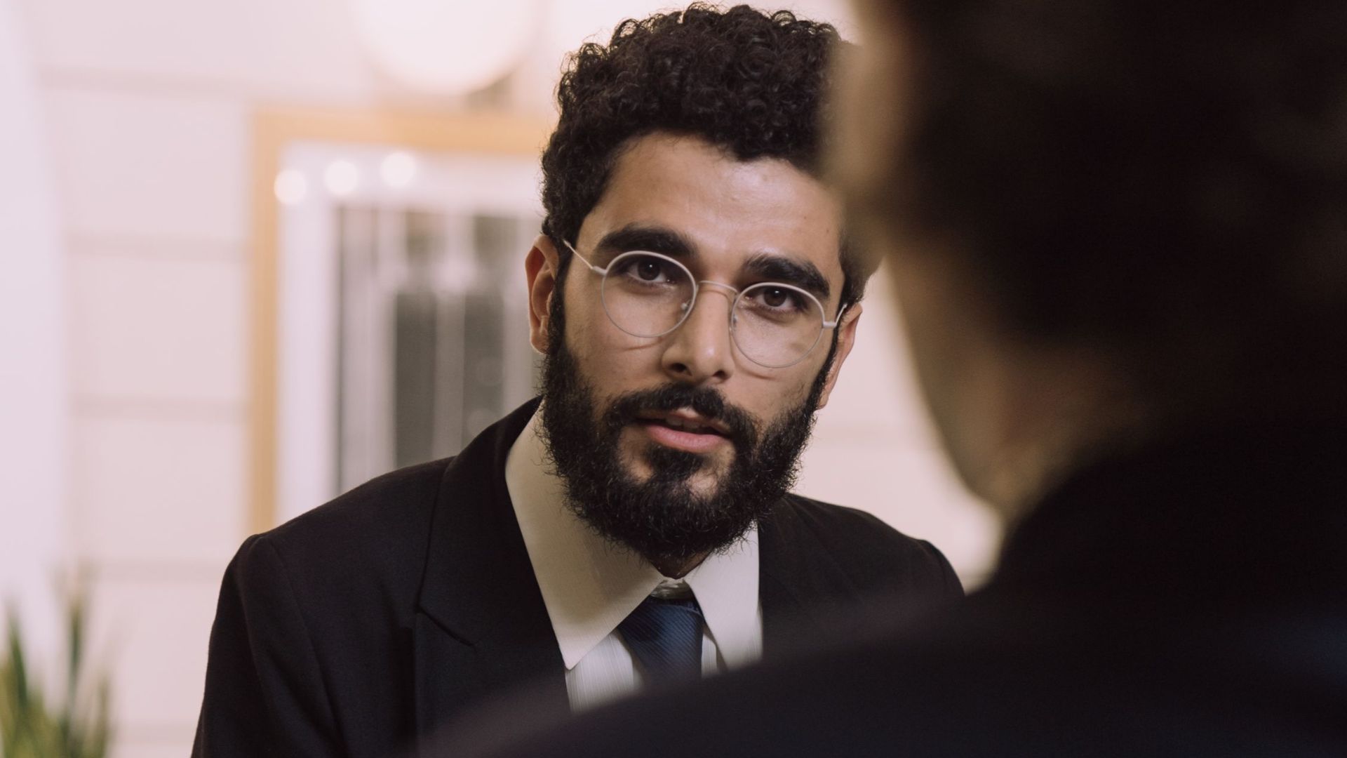A professional businessman checks in at a hotel reception, engaging with a concierge.
