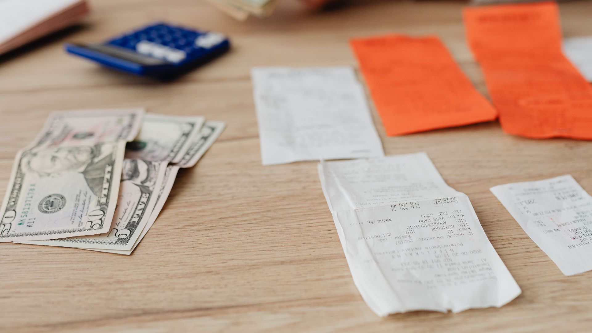 A person using a calculator and cash to plan a household budget.