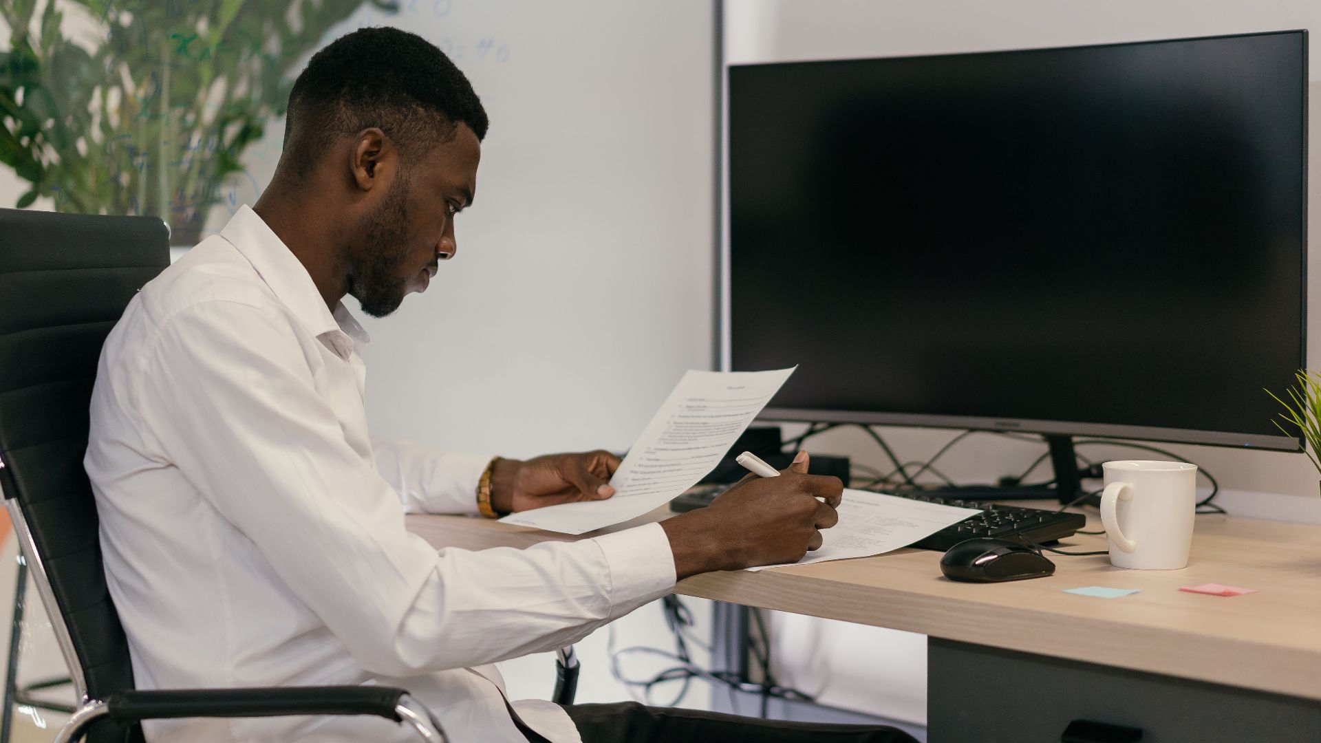 A focused professional working at an office desk with computer and paperwork. Ideal for business concepts.
