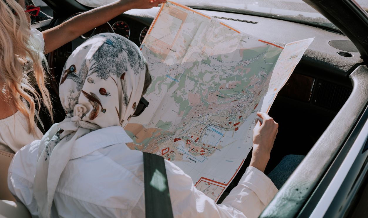 Two friends in a car navigating their road trip using a map