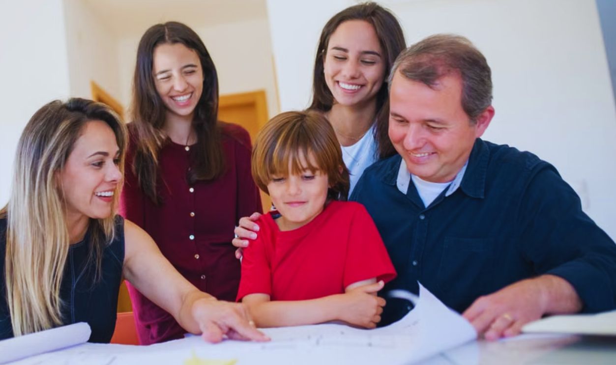 A joyful family gathered around a table reviewing a home blueprint together