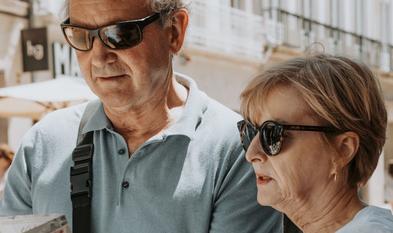 Senior couple enjoys sightseeing in Porto, Portugal, using a map on a sunny summer day