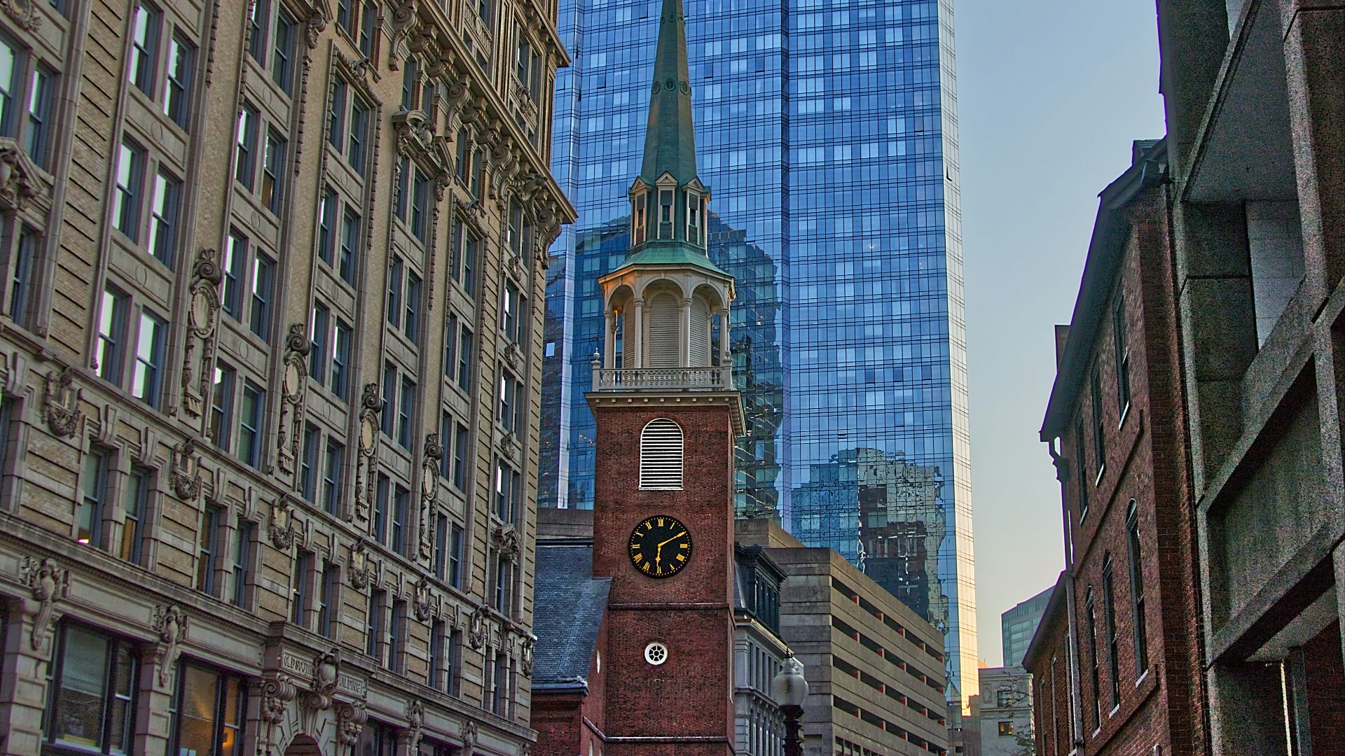 tower clock surrounded with high-rise buildings during daytime