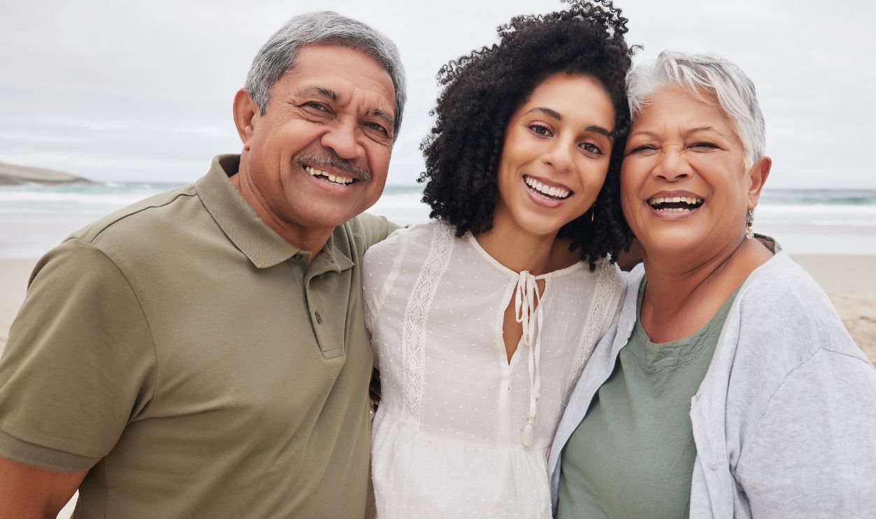Shutterstock-2368562857, Portrait, happy woman and senior parents at beach on holiday, vacation or travel outdoor. Face, adult daughter and mother and father bonding together at ocean for family connection, love and support
