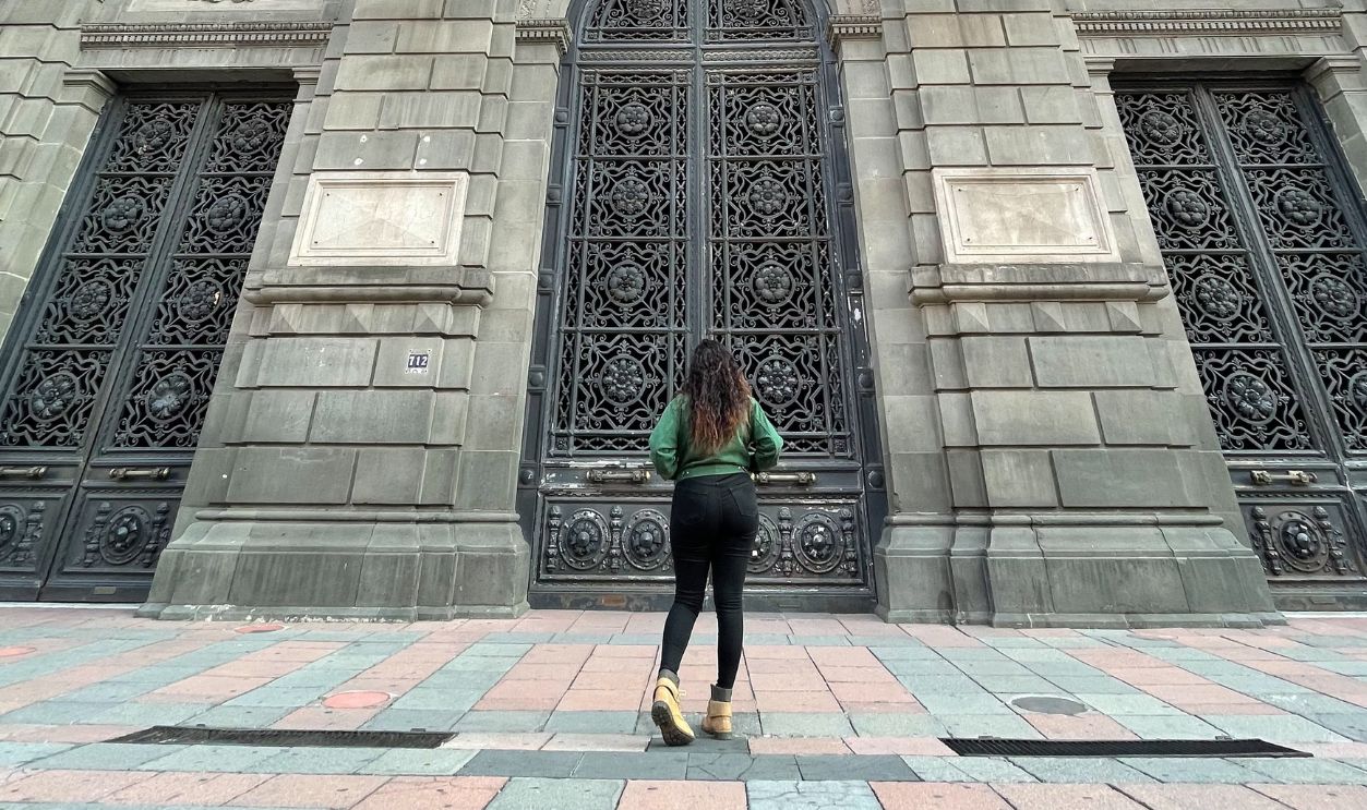Low angle view of a woman standing before the impressive facade of Museo Nacional de Arte in Mexico City