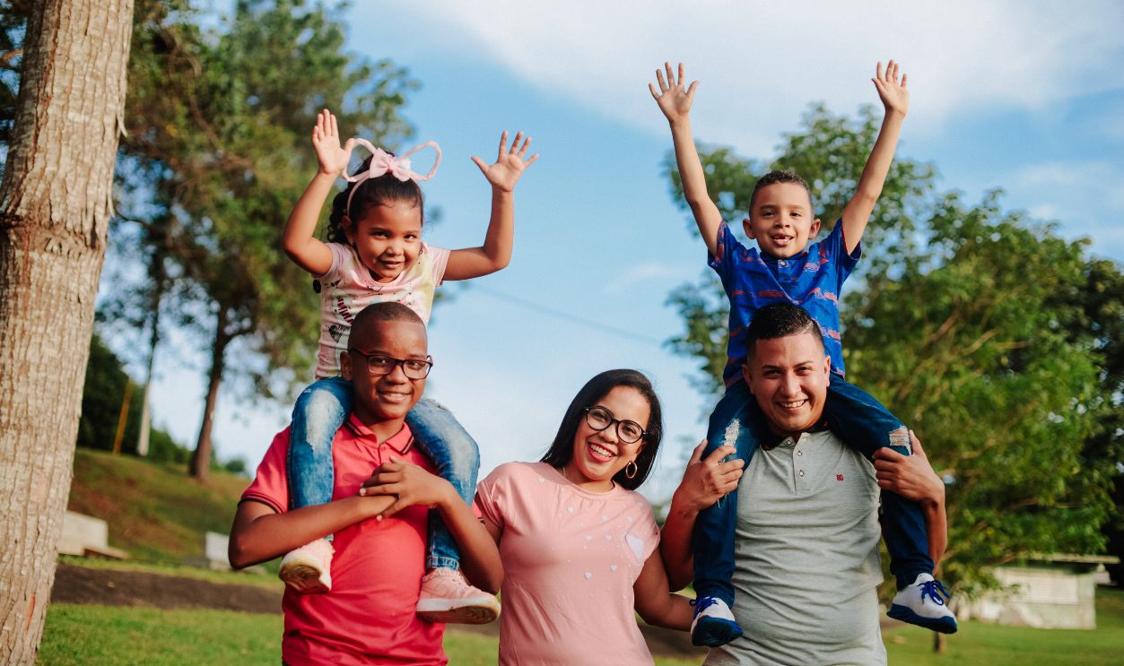 A joyful family spending quality time outdoors with kids on parents' shoulders