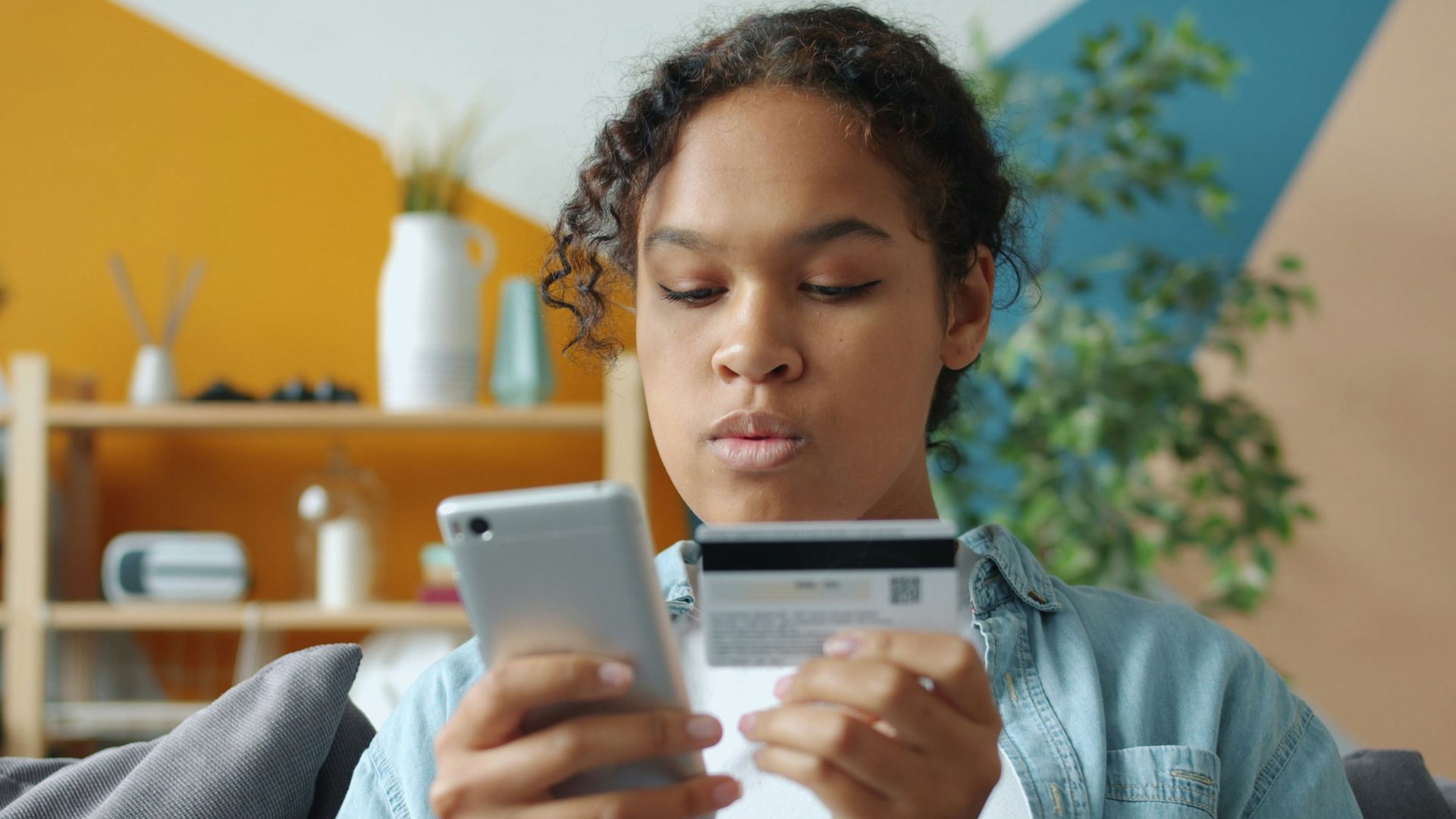 Woman holding credit card and phone for online shopping.