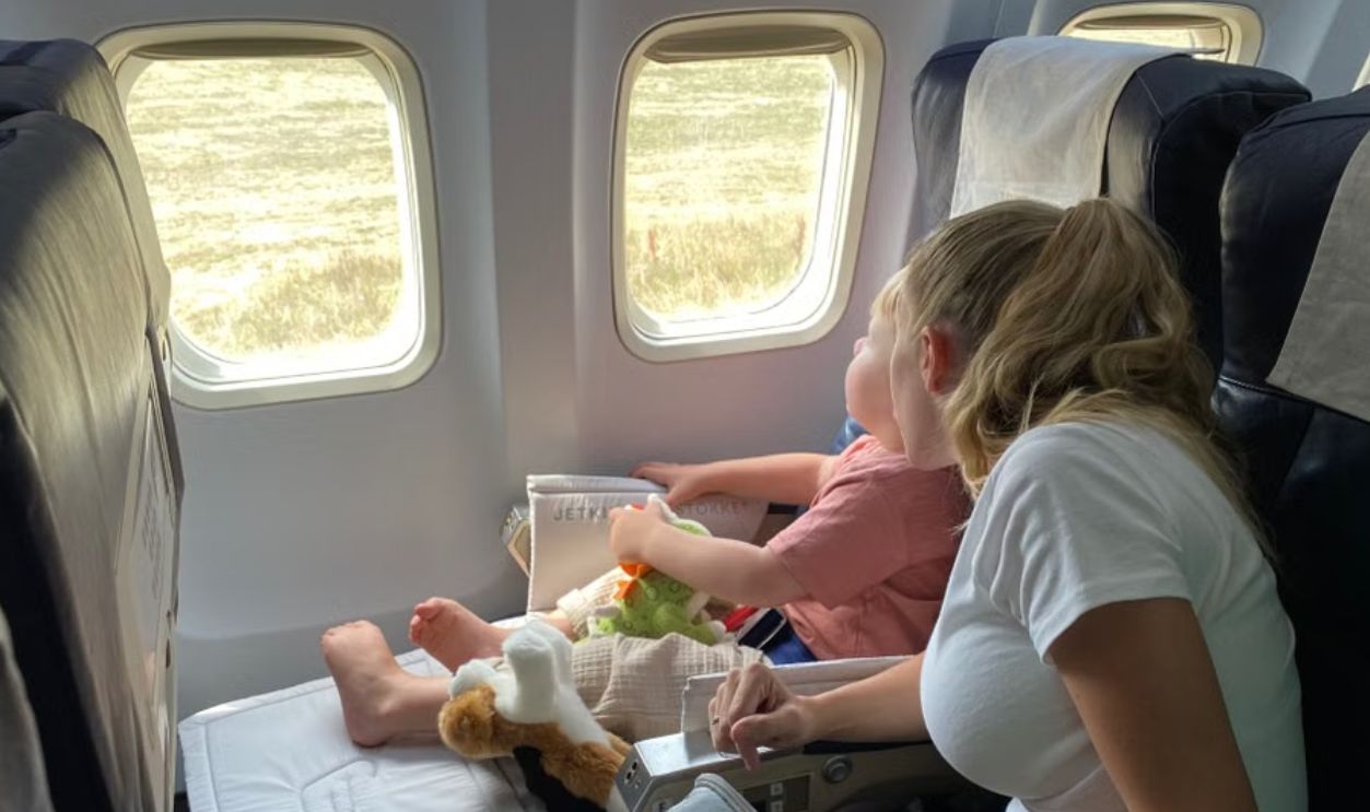 Mother and child sitting inside airplane, enjoying scenic view through windows during flight travel