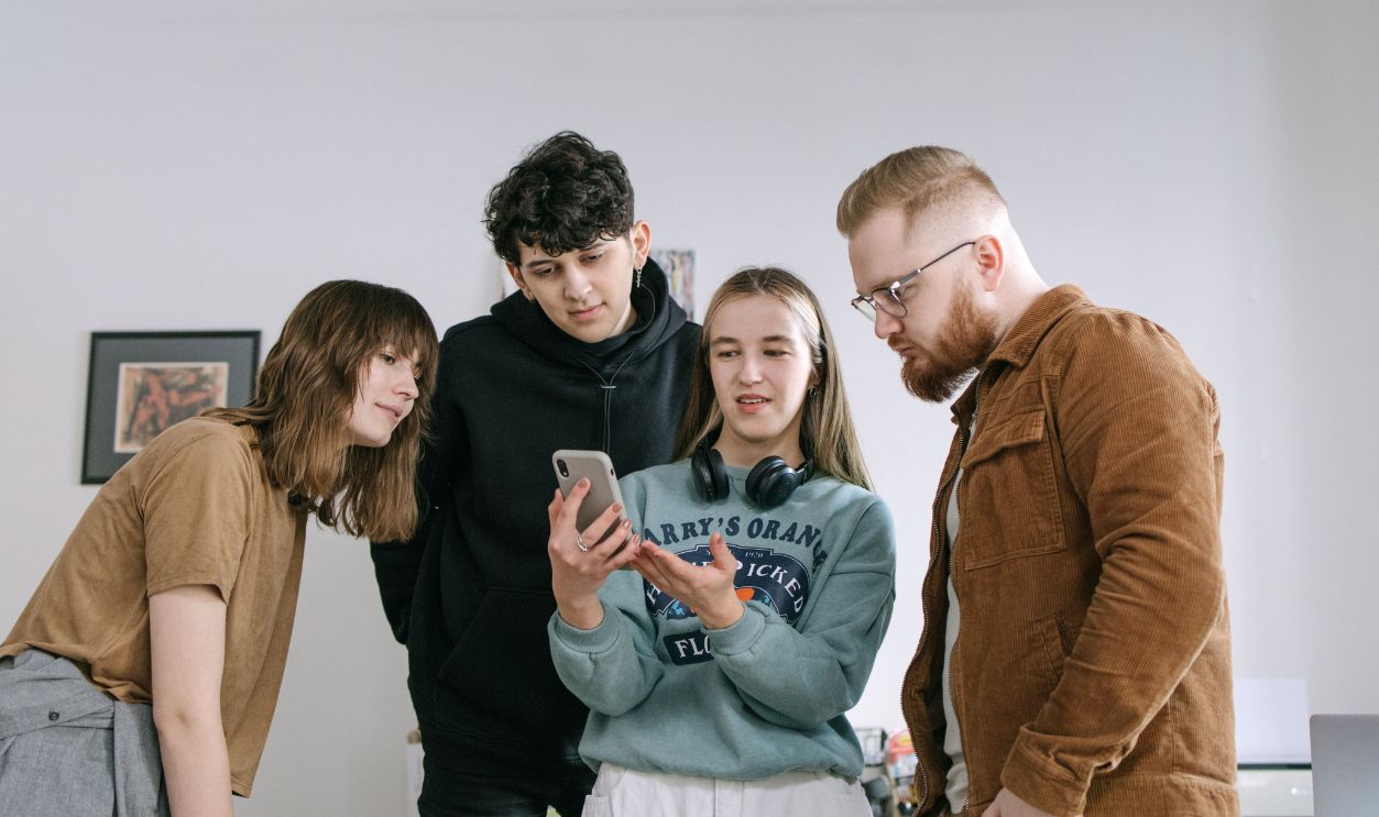 Group of young adults reviewing content on a smartphone in an office 
