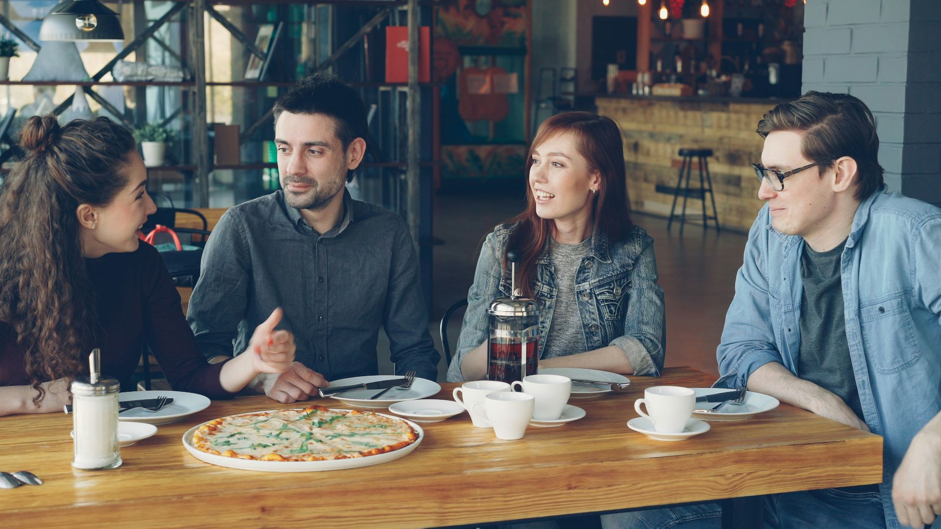 Friends enjoy pizza and conversation in a restaurant.