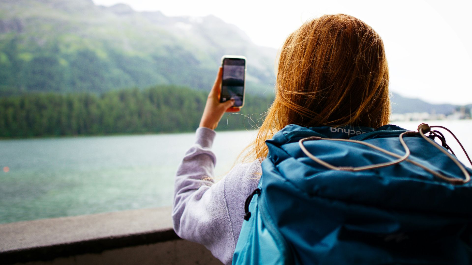 woman in gray jacket holding smartphone