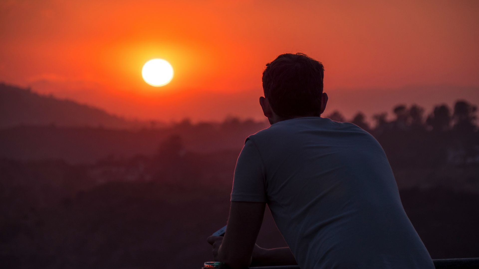 man wearing blue shirt looking at sunset