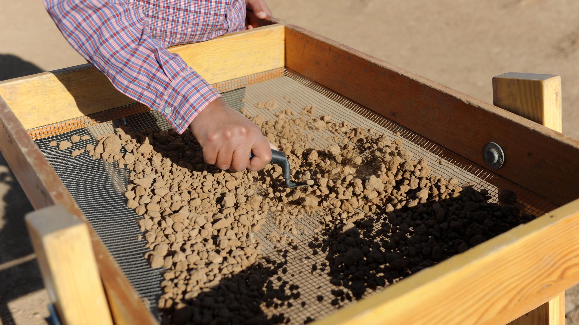 Rachelle Robinson, archaeological field technician, screens dirt for artifacts at Archaeological Site 419, Luke Air Force Base, April 12. Dirt from the digging is screened and scanned to find small artifacts that may be missed by the human eye.