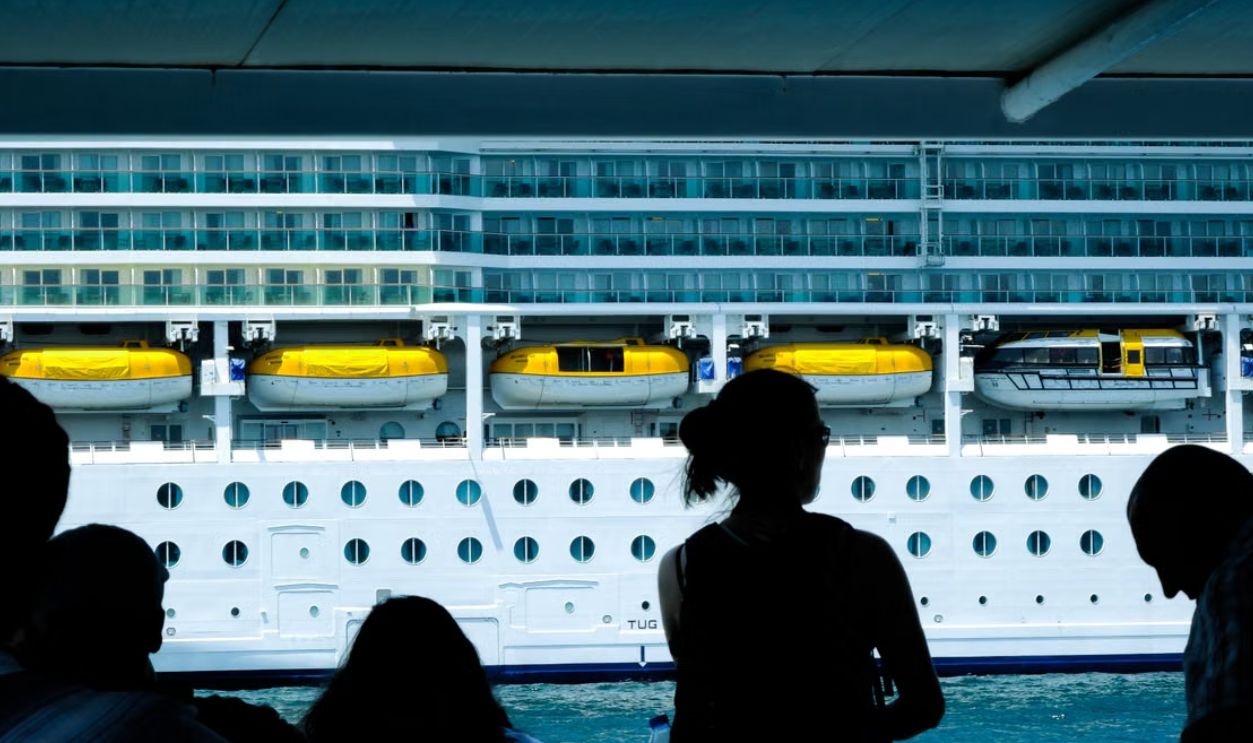 Silhouettes of people observing a large cruise ship from a dock in Turkiye
