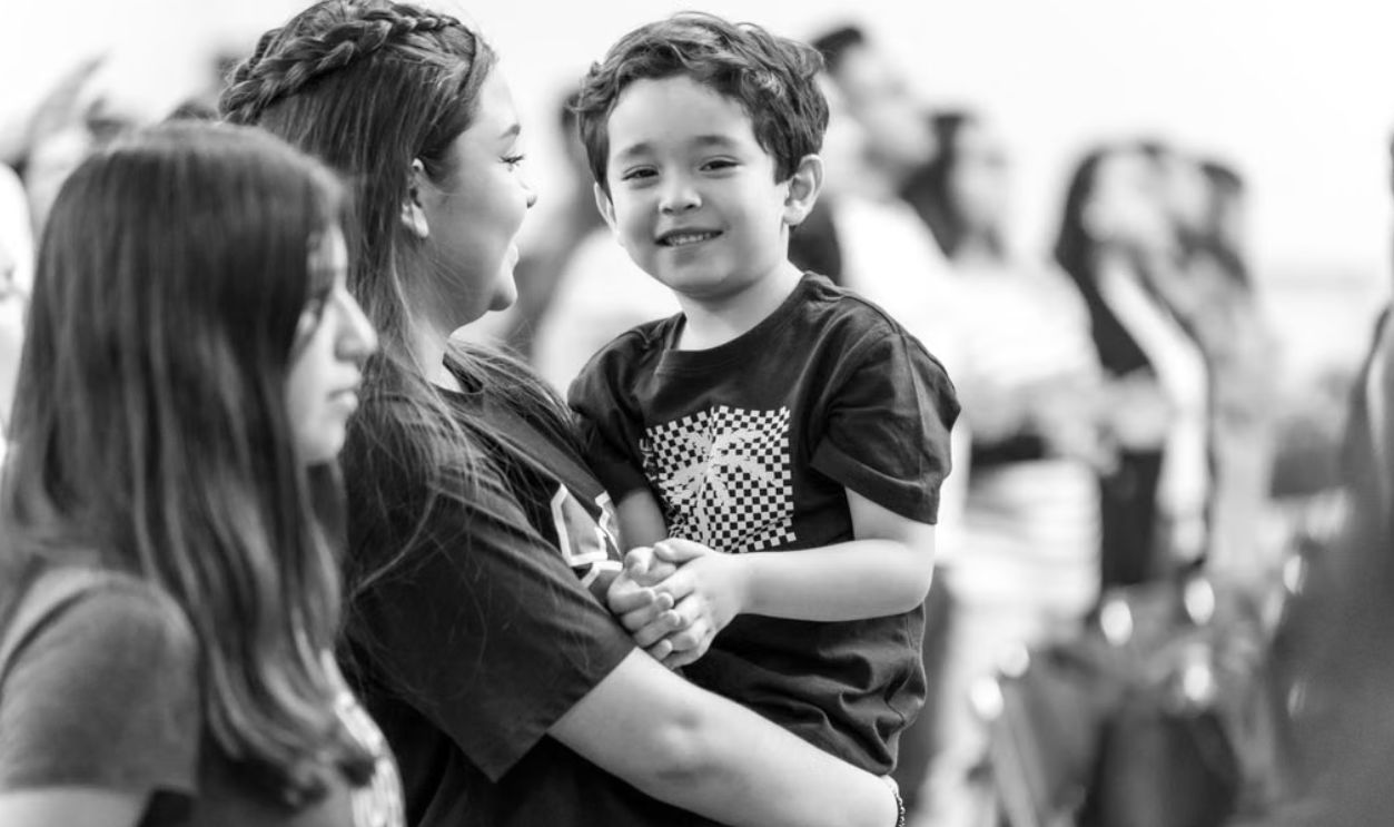 A heartwarming black and white portrait of a smiling boy held by his family, exuding happiness and love