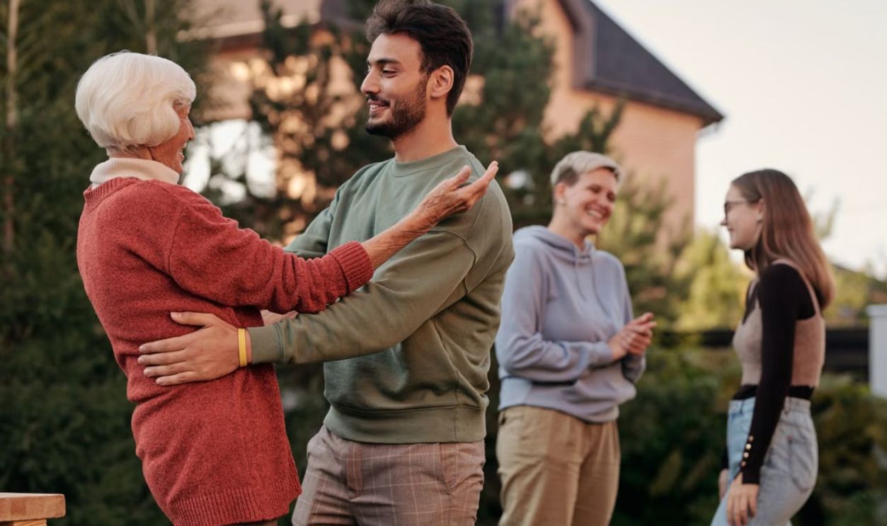 A joyful family gathering outdoors with diverse generations embracing and smiling