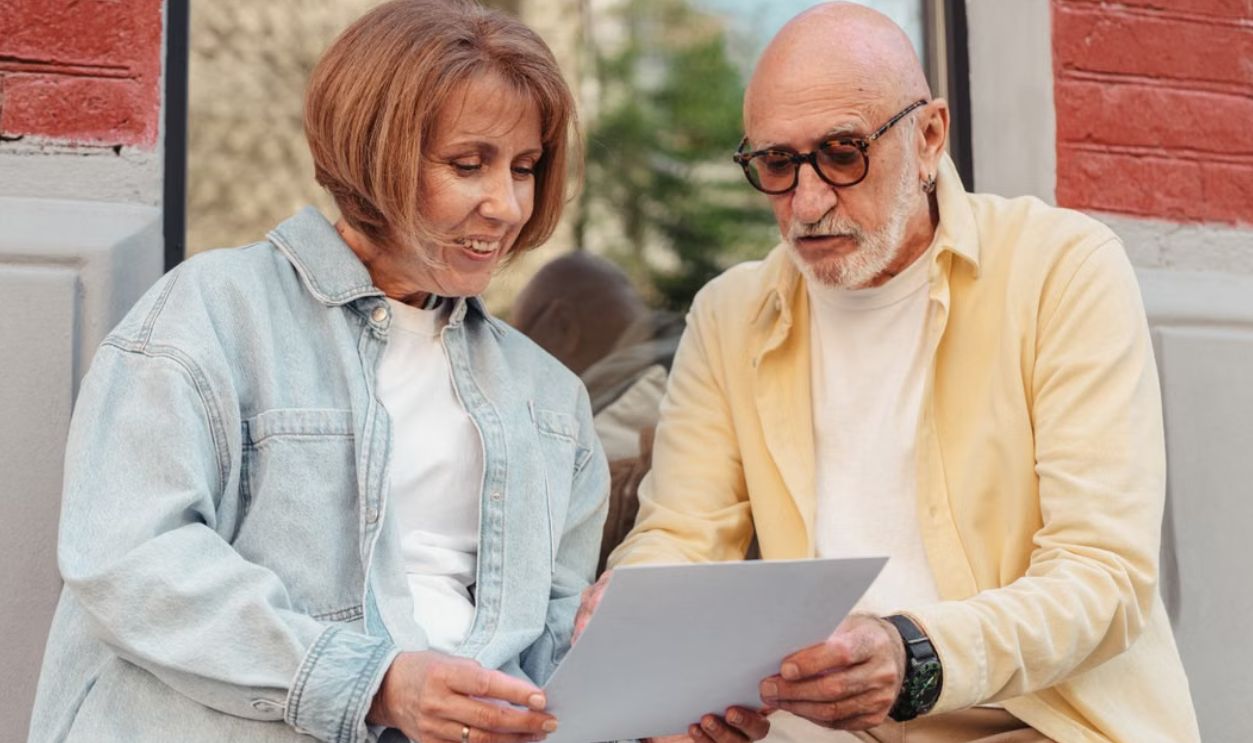 Elderly couple reading a document together while sitting outside at a cafe