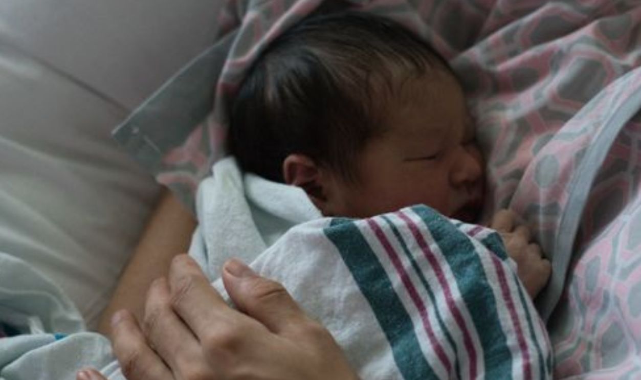 A peaceful scene of a mother cuddling her sleeping newborn in a hospital setting