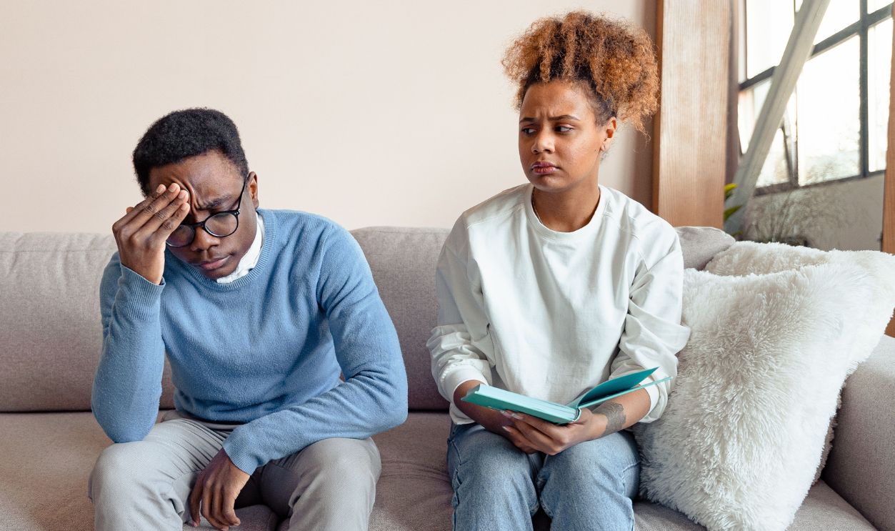 Two people sitting on a sofa indoors, engaged in a serious discussion during a therapy 