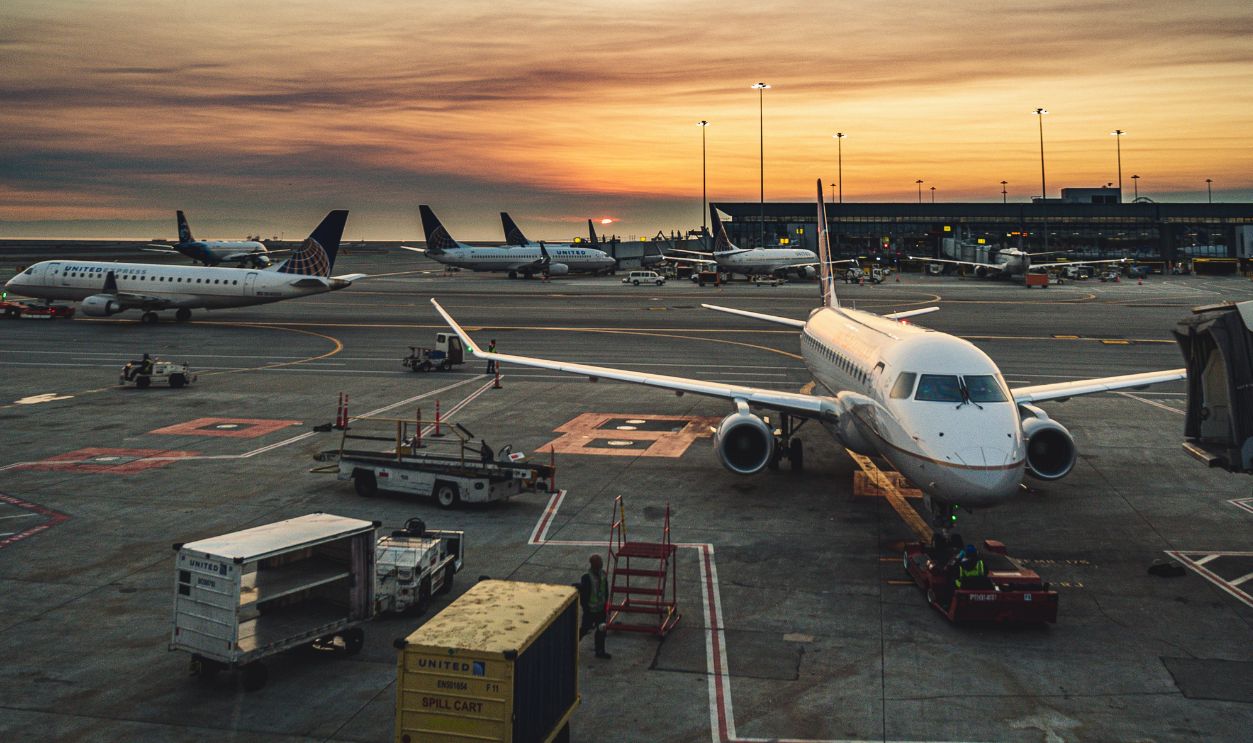 Airplanes parked at a busy airport terminal during sunset, showcasing aviation and travel