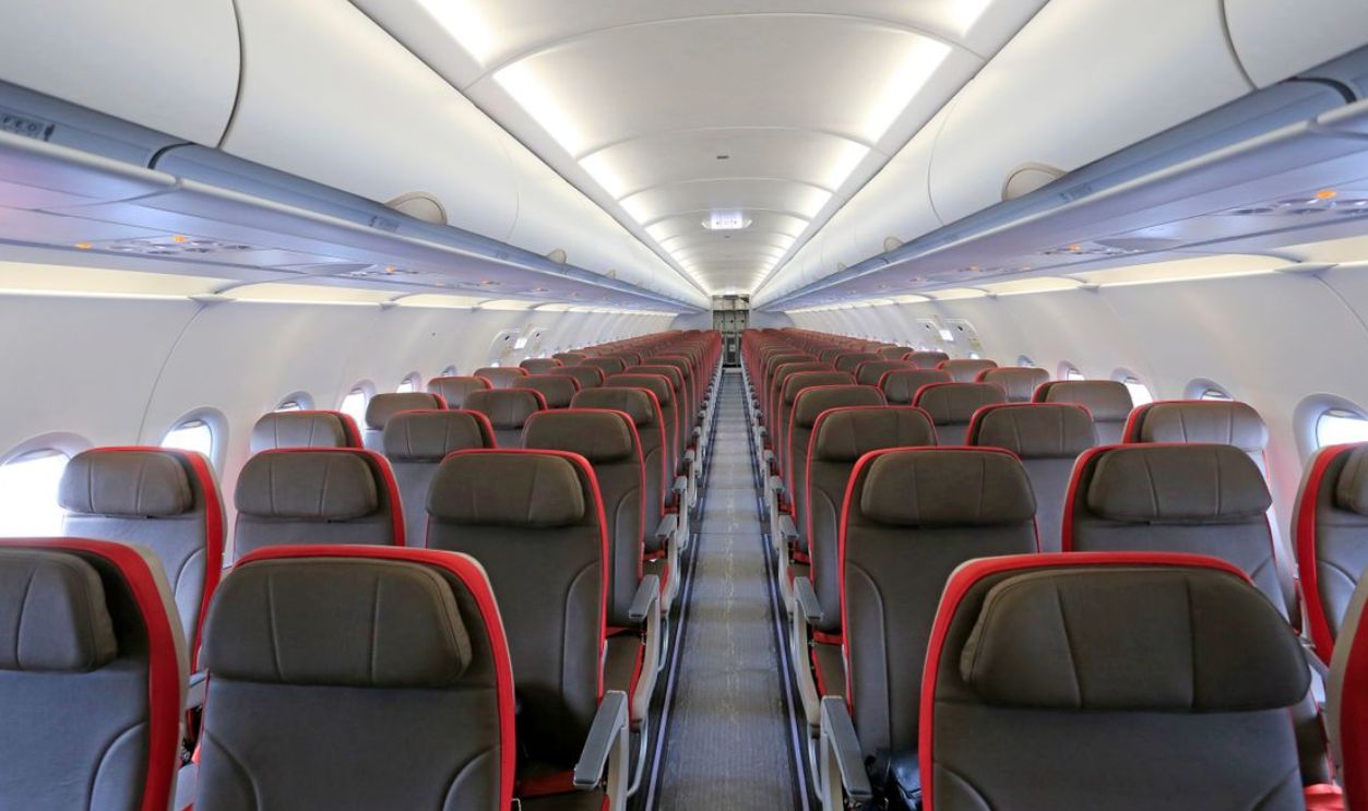 Wide view of an aircraft cabin with empty rows of seats, ready for boarding