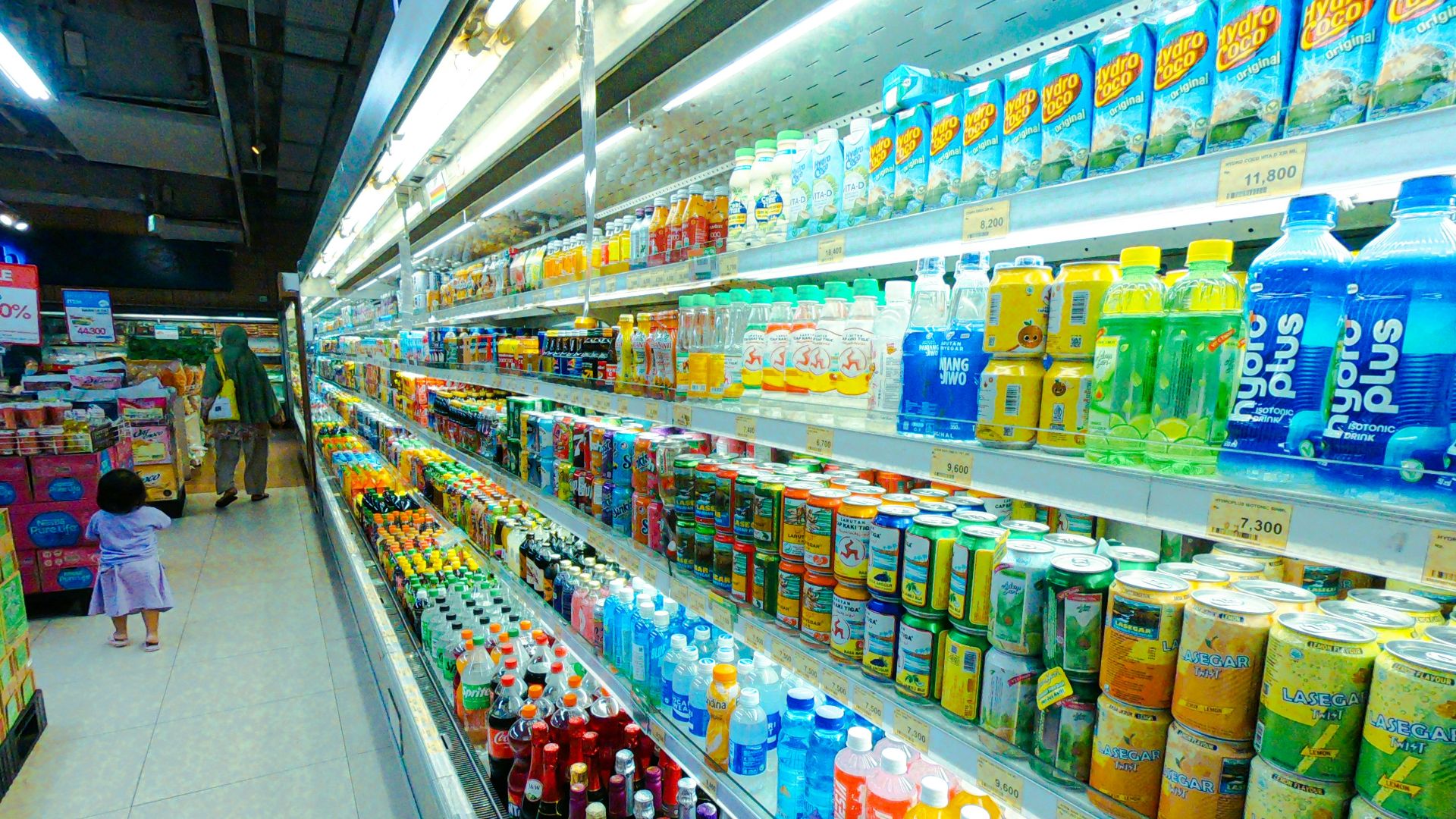 A refrigerator aisle is stocked with drinks.