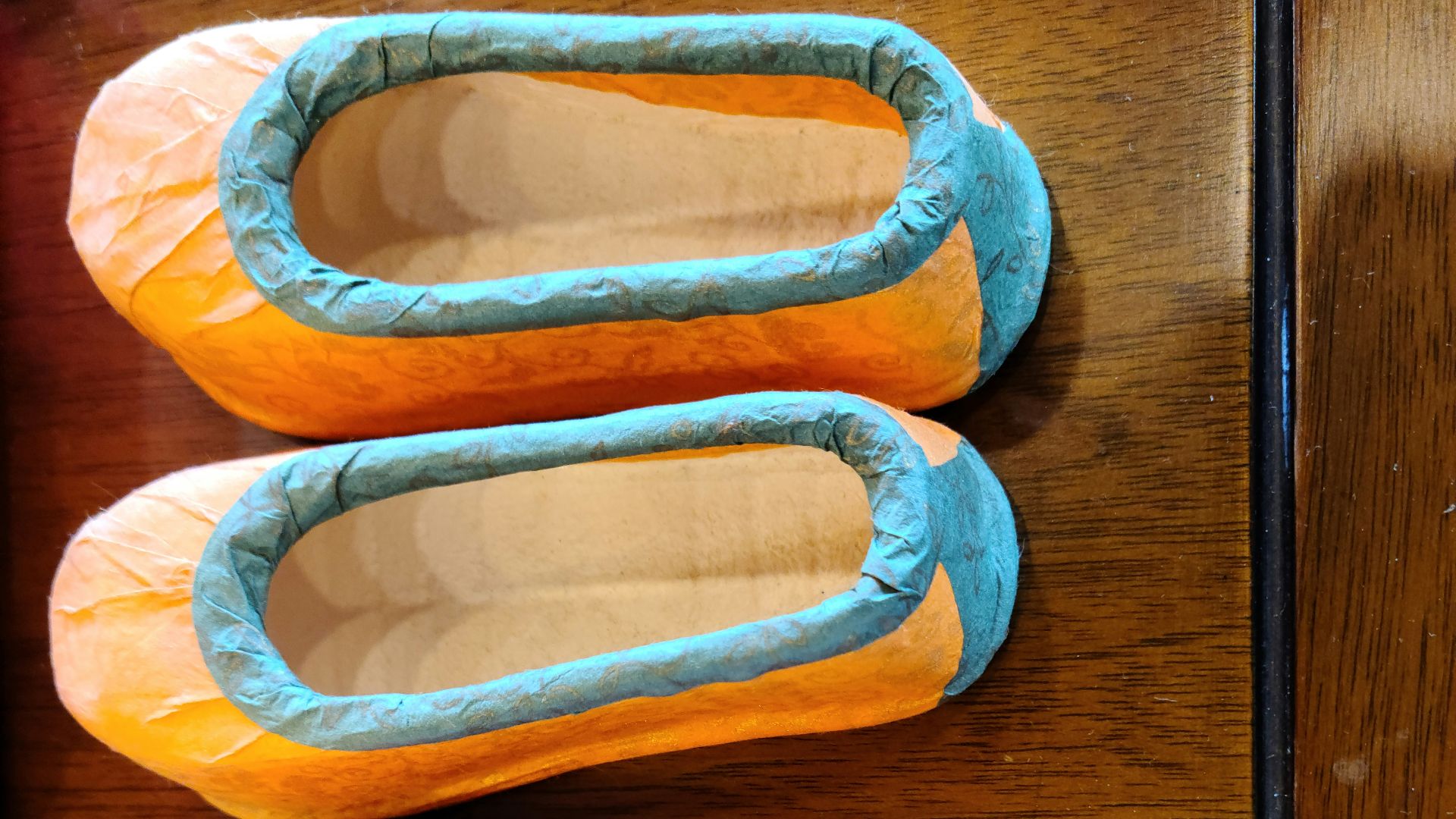 three pairs of slippers sitting on top of a wooden table
