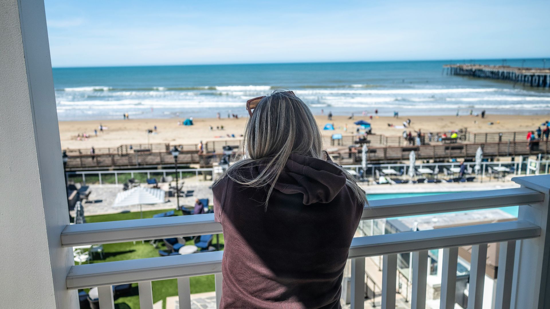 a woman standing on a balcony looking out at the beach