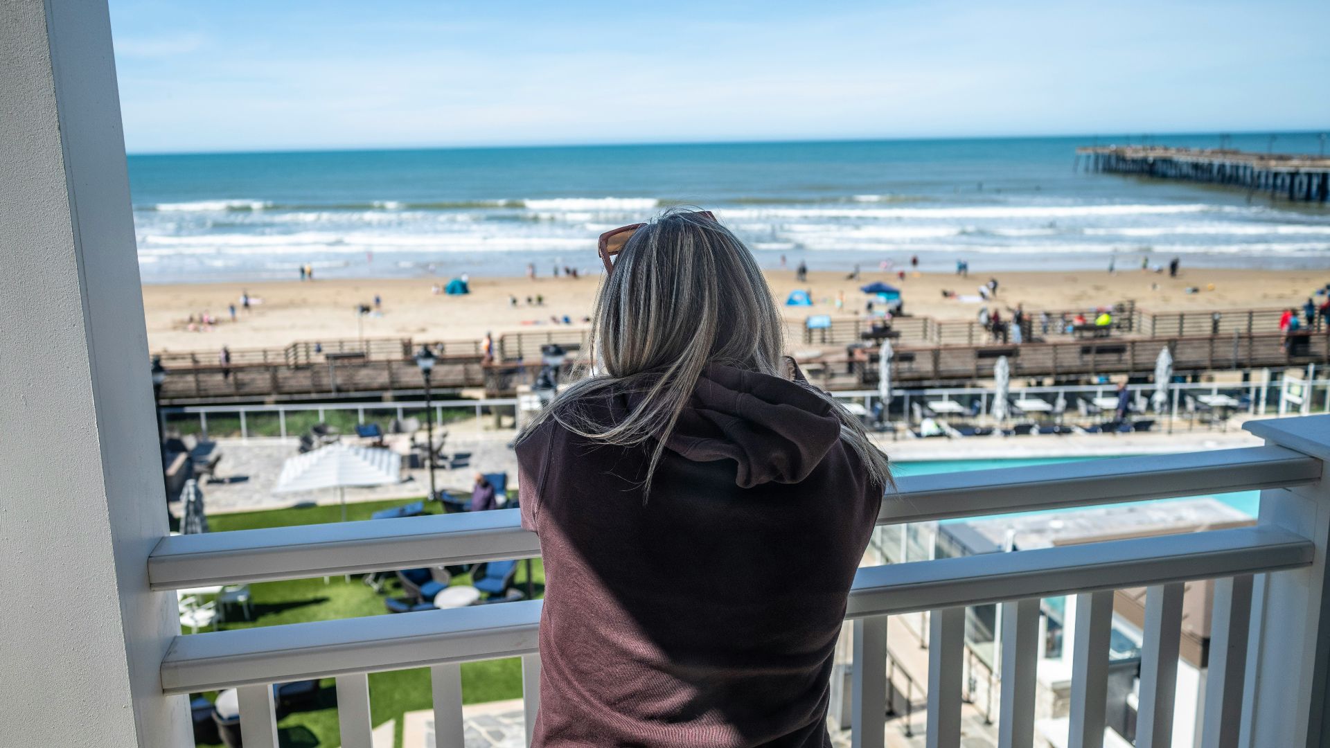 a woman standing on a balcony looking out at the beach