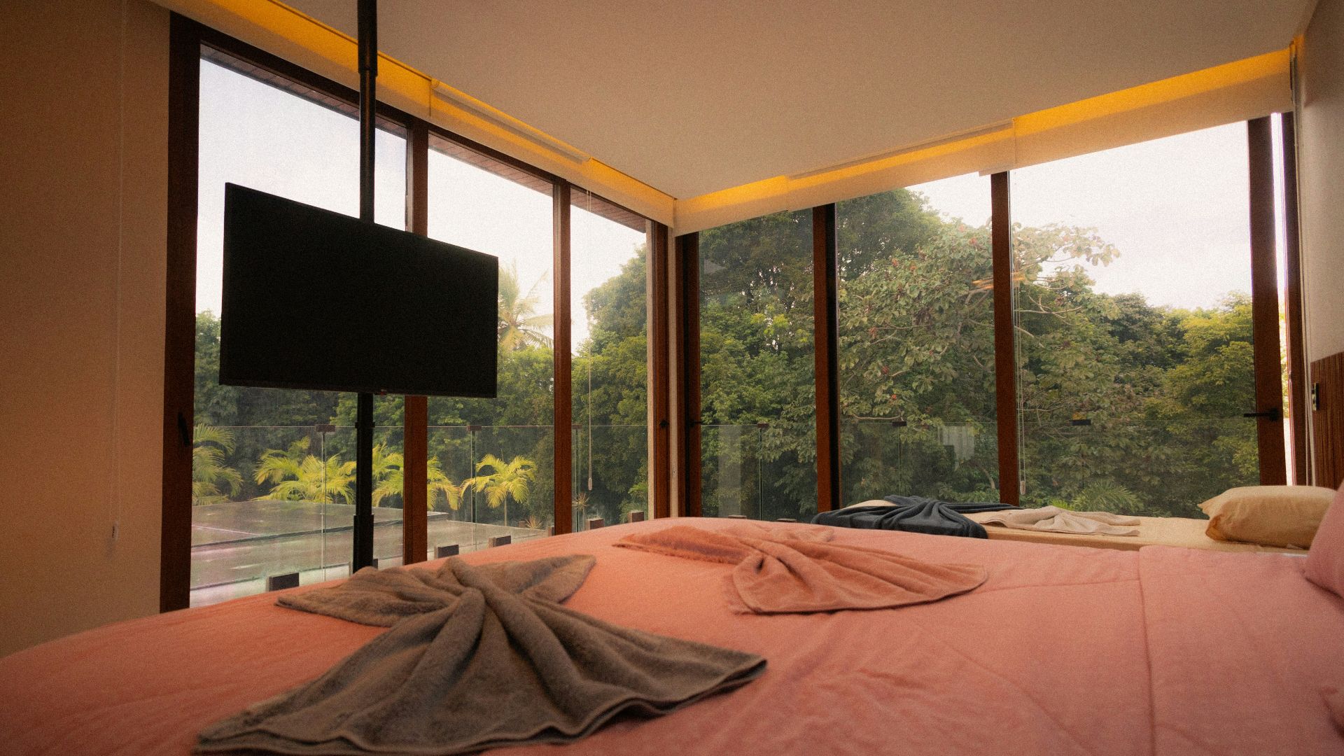 Bedroom with large windows overlooking lush green forest